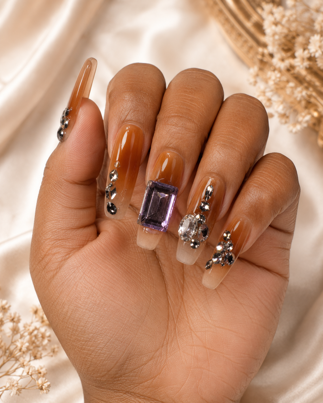 Jewel Luxe press-on nails worn on hand – caramel ombre with amethyst gem and crystal embellishments
